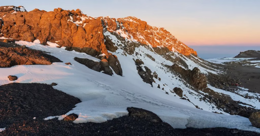 Trekker reaching Uhuru Peak on Mount Kilimanjaro during Tanzania adventure travel.