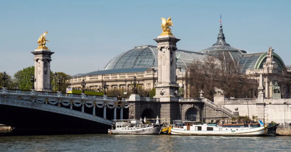 Pont Alexandre III illuminated at night with golden statues and warm lighting.