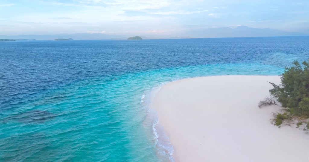 Pristine white sand beach on Ile Mandiri island with clear blue water